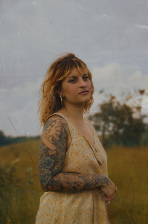 Woman with Tattooed Arms Standing in the Meadow 