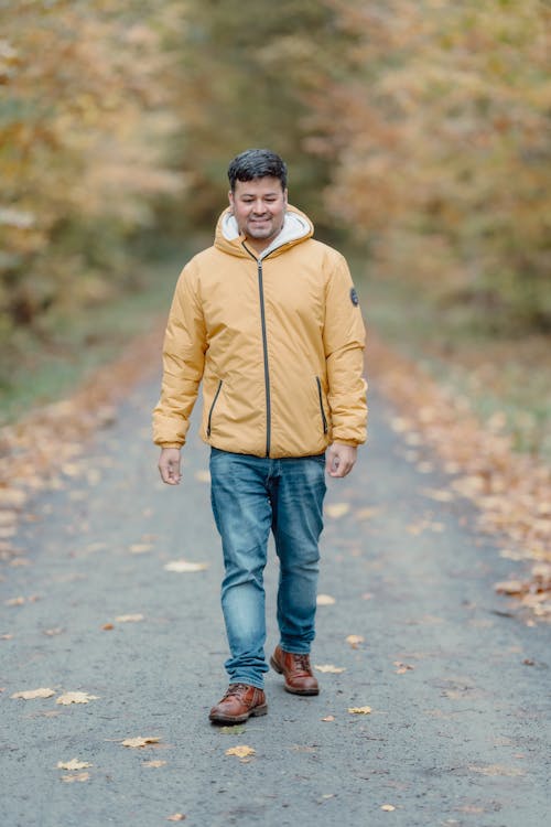 Man in Yellow Jacket on Dirt Road in Forest