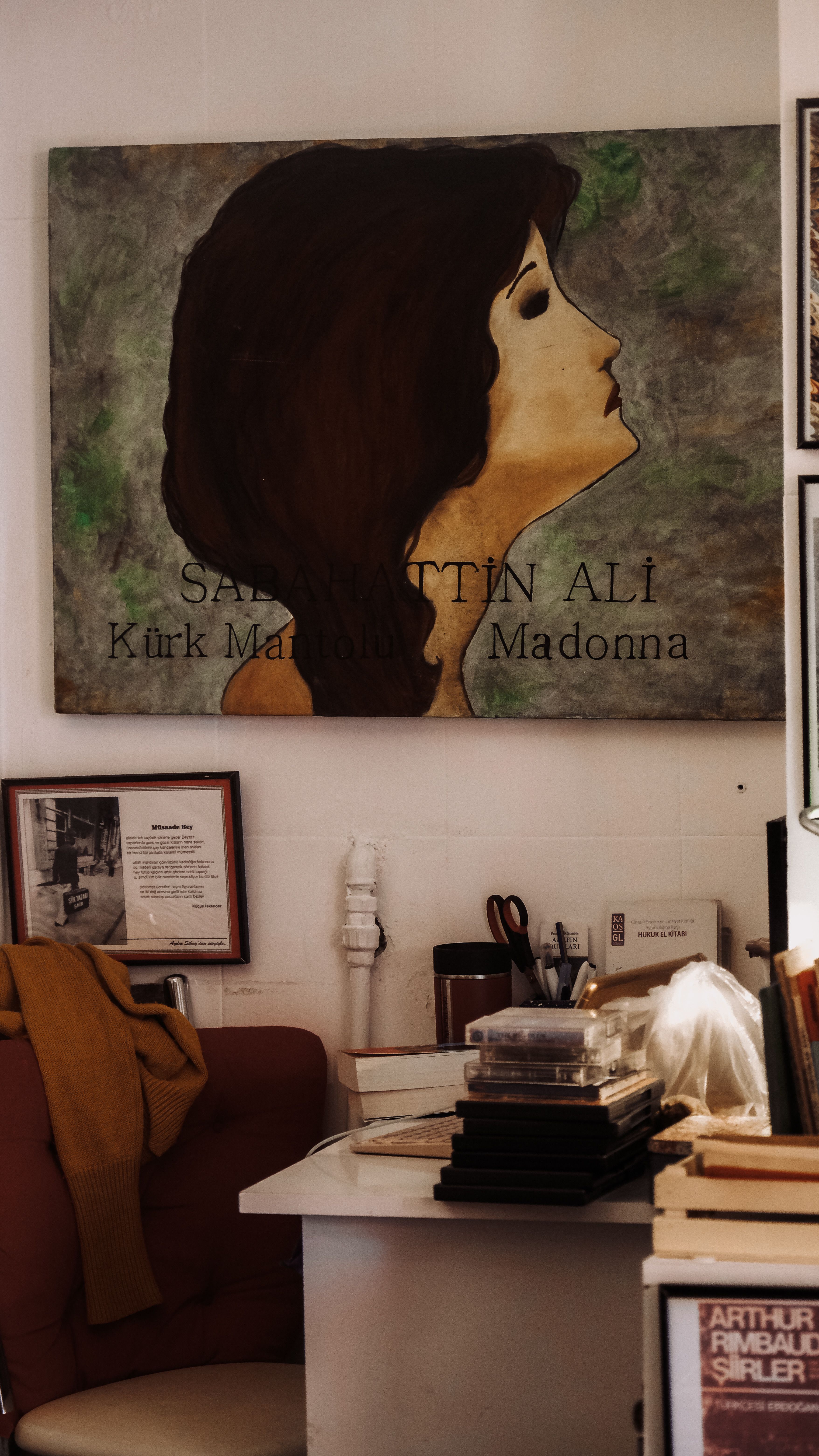 A cozy office space featuring a framed portrait artwork with books and accessories.