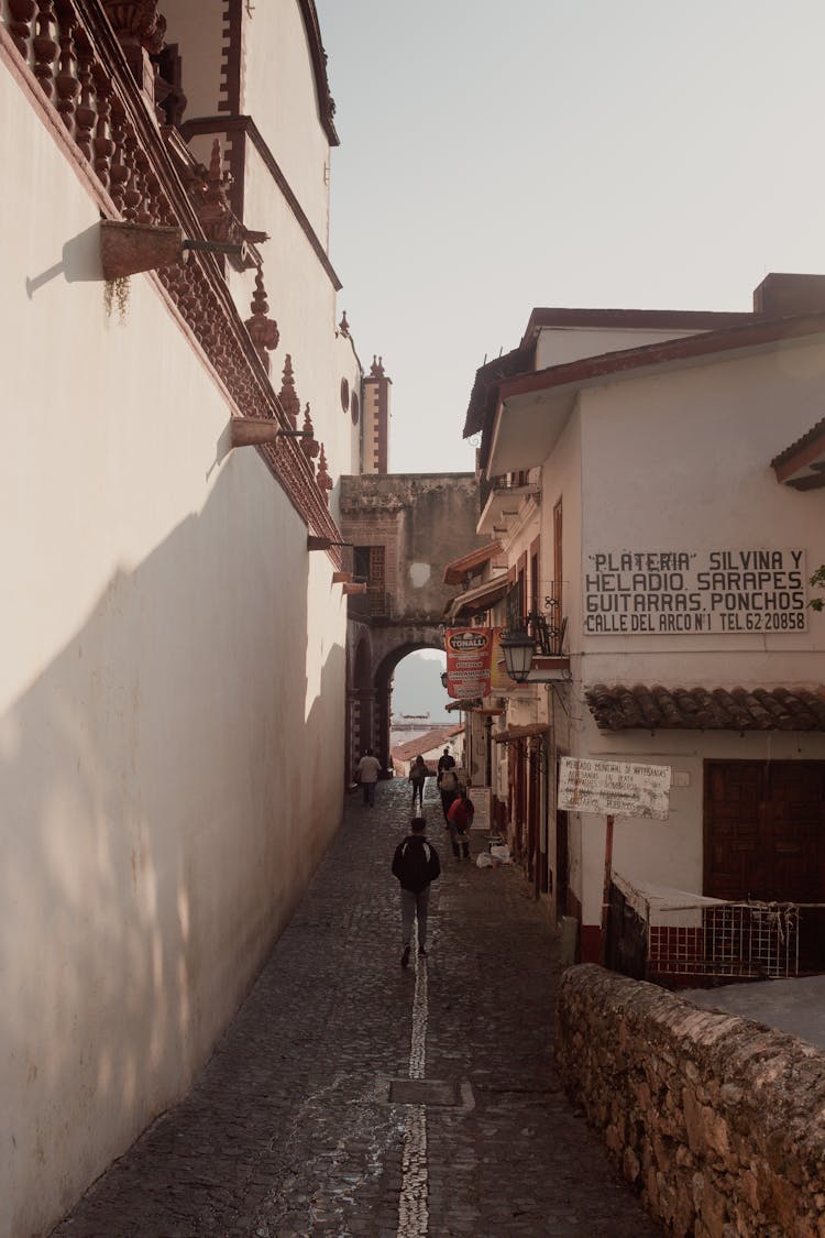 People Walking In Narrow Alley In Town