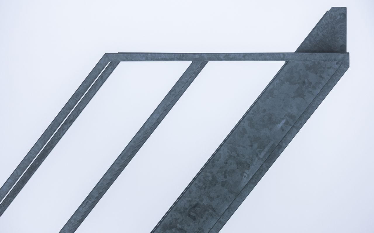 minimalist view of abstract diagonal metal beams set against a clear s