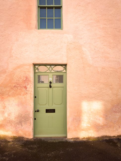A sunlit green door set in a pastel pink wall, perfect for urban vintage themes.