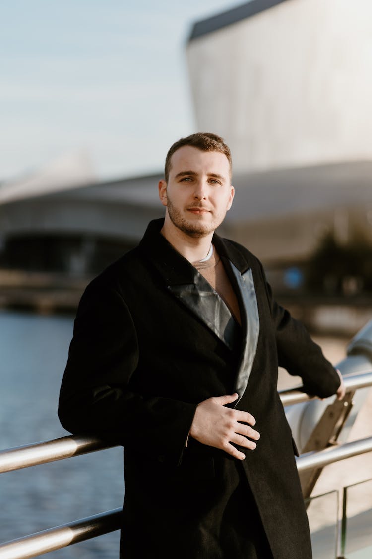 Man In Black Double Breasted Woolen Coat Leaning On Metal Railing