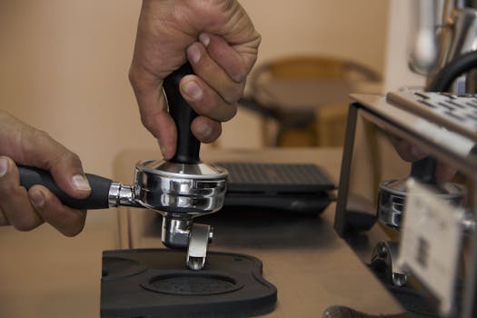 Detailed close-up of a barista using a coffee tamper to prepare espresso in Bogotá, Colombia.
