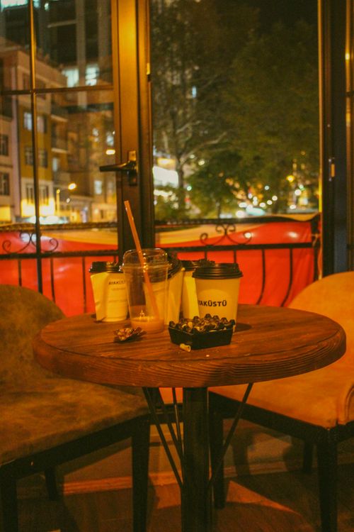 Free Inviting scene of a café table with coffee cups and snacks by a window during a quiet night in Bilecik. Stock Photo