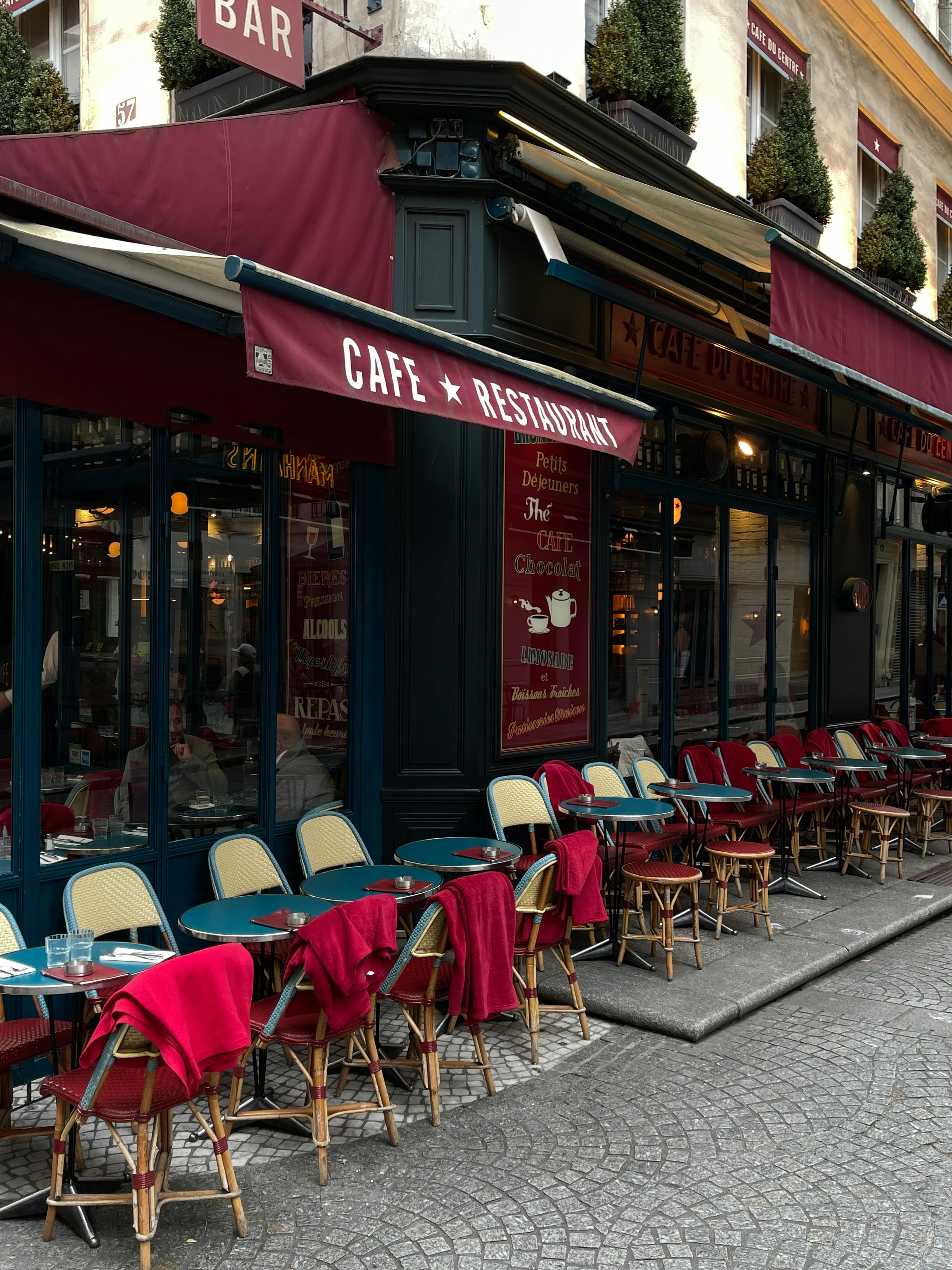 Classic Parisian café with red awnings and bistro tables on a cobblestone street.