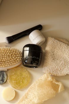 A flat lay of natural skincare products including jars, brushes, and sponges on a neutral background.