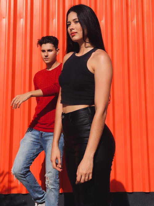 Young Man and Woman Standing Outside on the Background of an Orange Building 