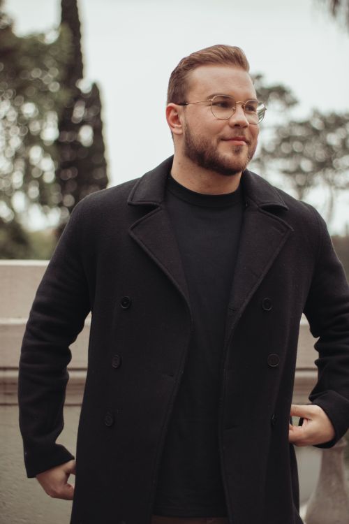 Free A fashionable man in a black double-breasted coat standing outdoors, exuding confidence. Stock Photo