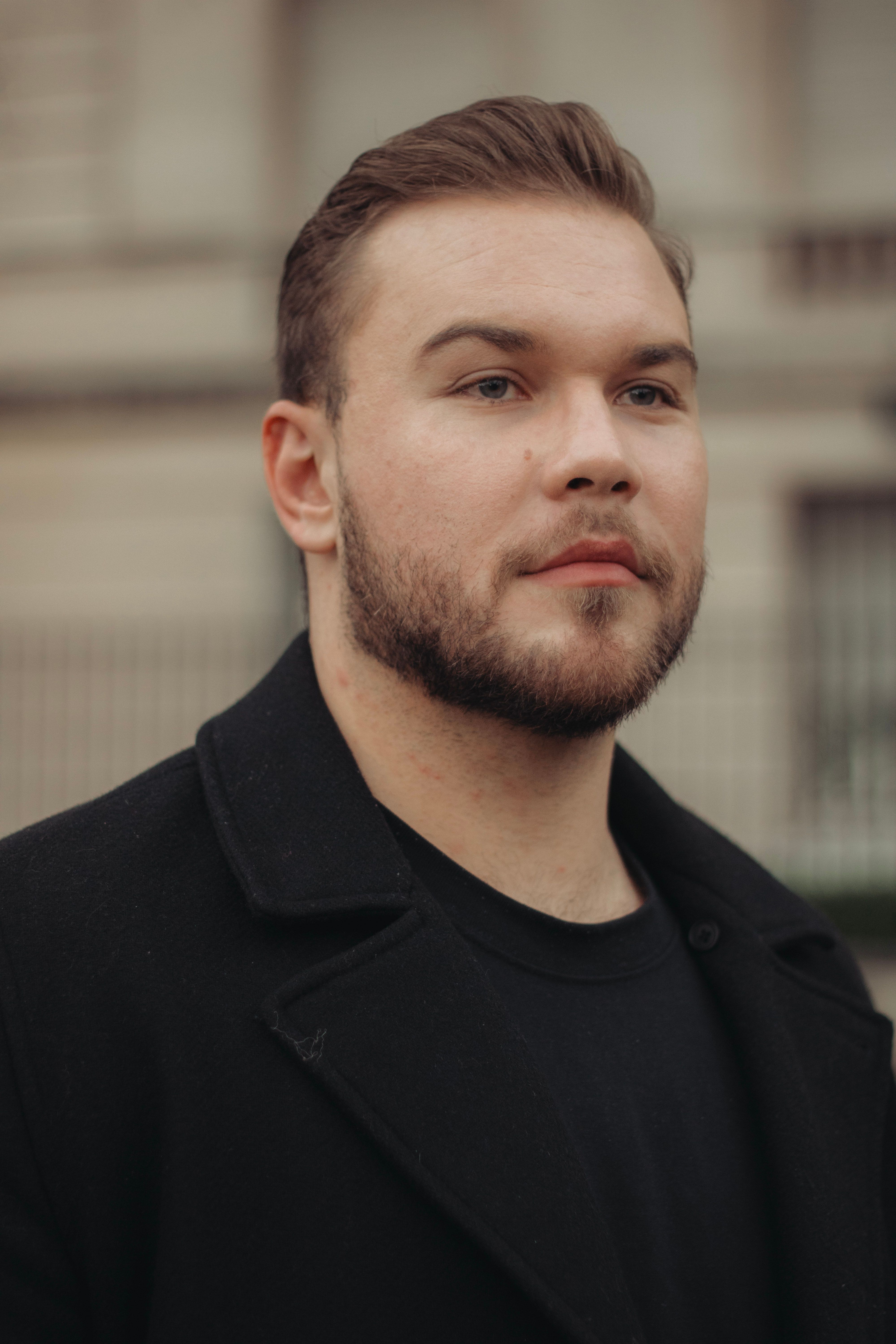 Portrait of a confident man with beard in a city setting, embodying elegance and fashion.