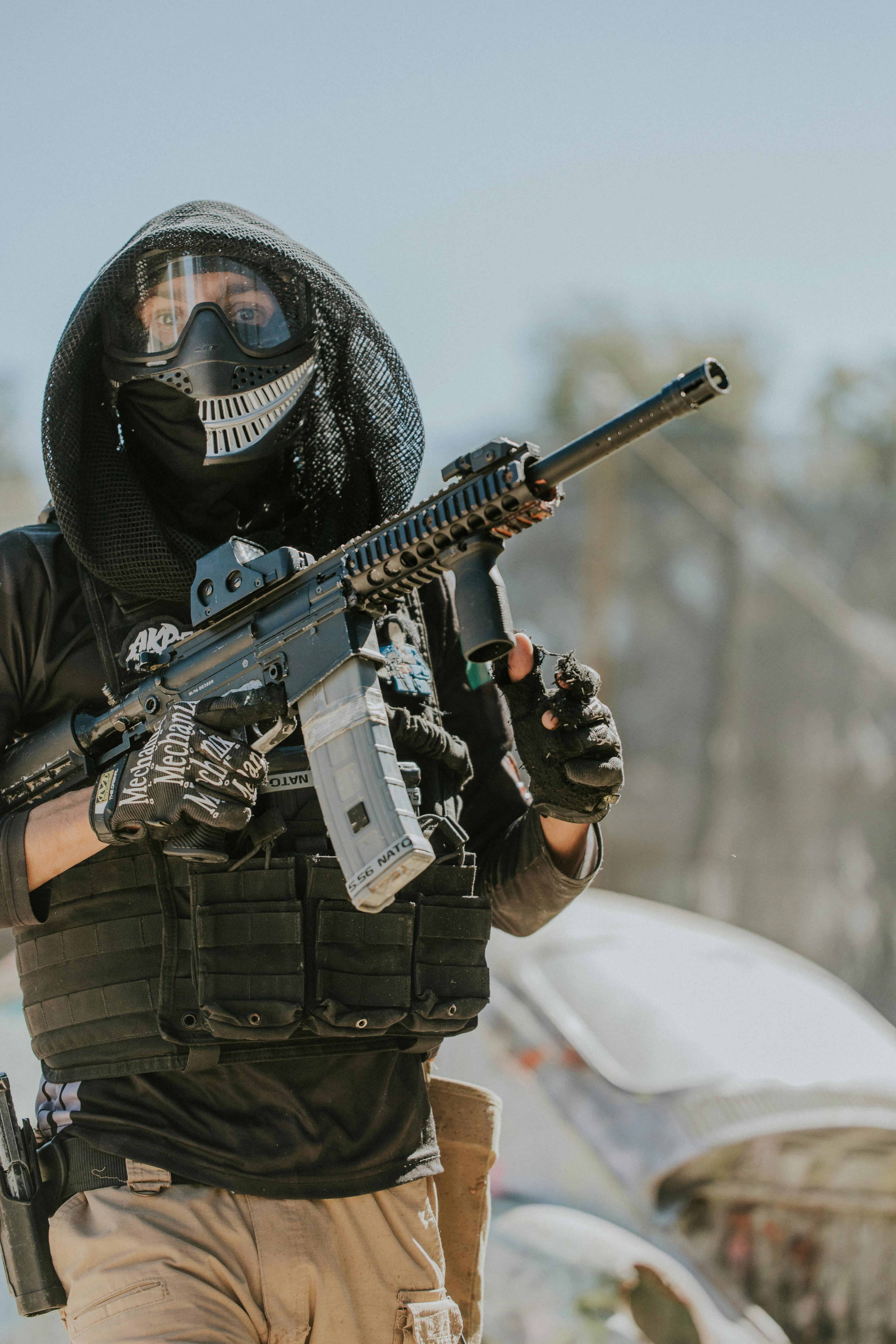 A paintball player dressed in tactical gear and mask holding a paintball rifle outdoors. Prescription Goggle Inserts - A paintball player dressed in tactical gear and mask holding a paintball rifle outdoors.