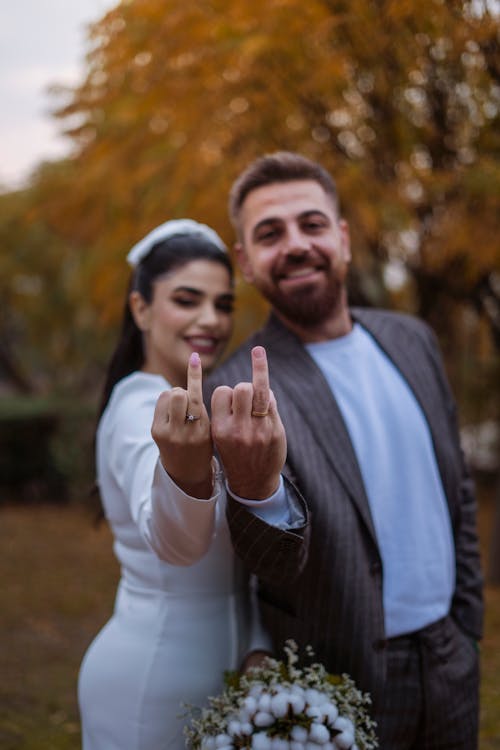 Bride and Groom Standing in a Park in Autumn and Smiling 