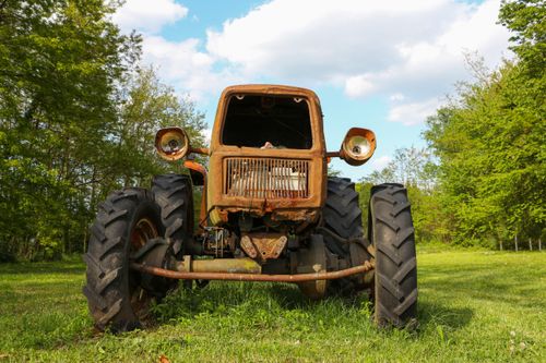 Free Front view of a rusty vintage tractor in a sunny rural field. Stock Photo