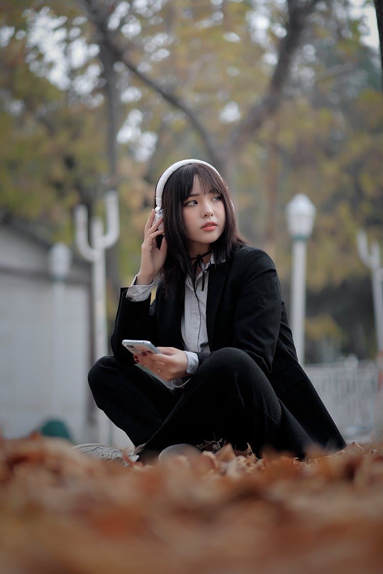 Young Woman With Headphones On Sitting Outside 