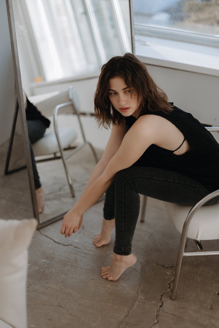 Barefoot Brunette In Black Sitting On Chair