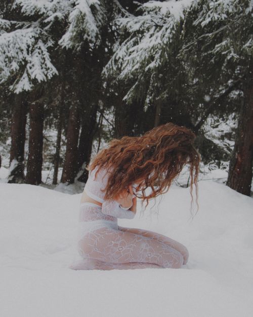 Free A woman in a forest during winter surrounded by snow, posing elegantly with curly hair. Stock Photo