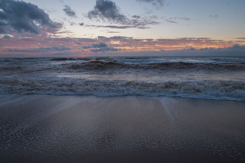Free Calm ocean waves under a vibrant sunrise sky, perfect for wallpaper. Stock Photo