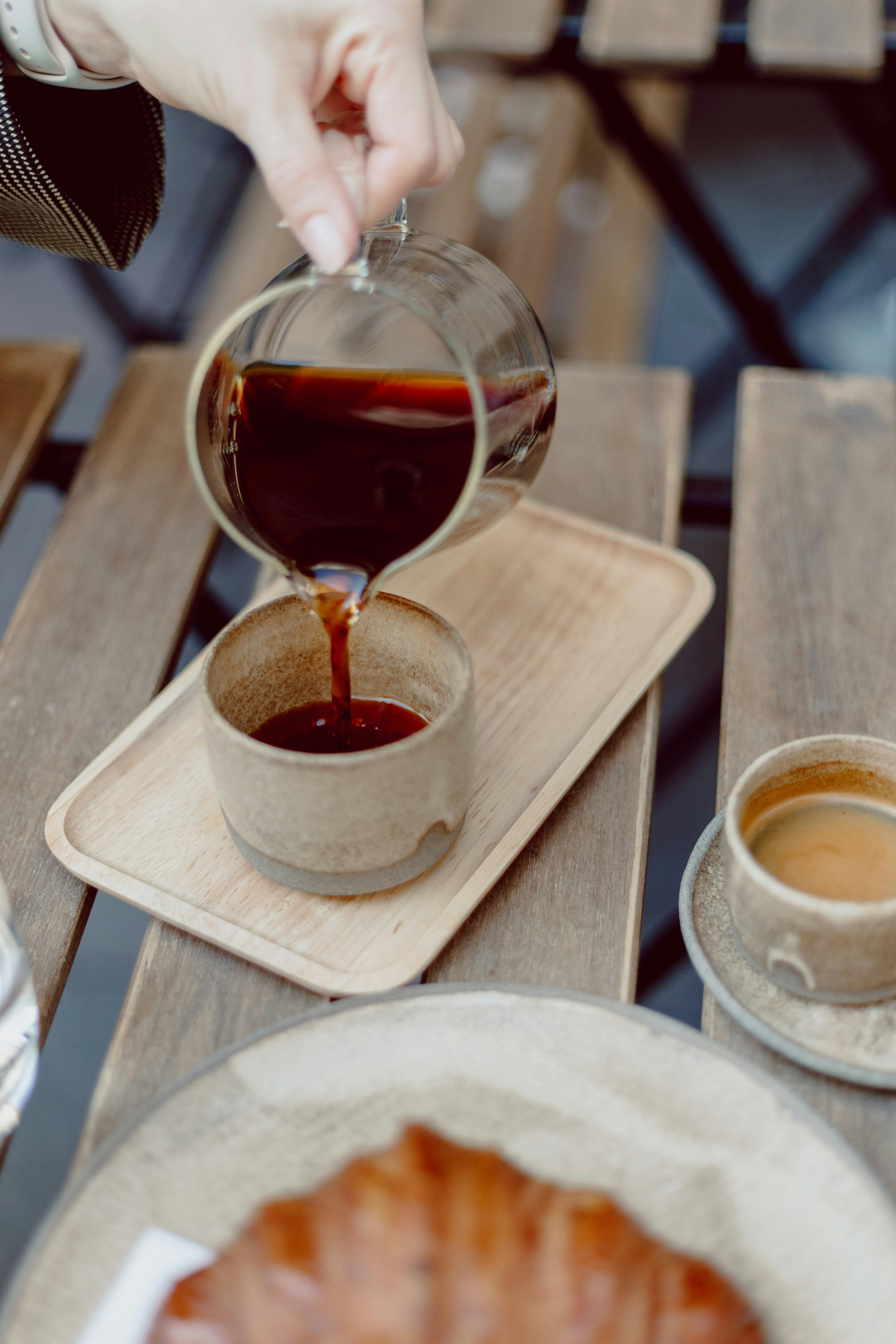 A serene café moment with coffee being poured by hand into a ceramic cup in Budapest.