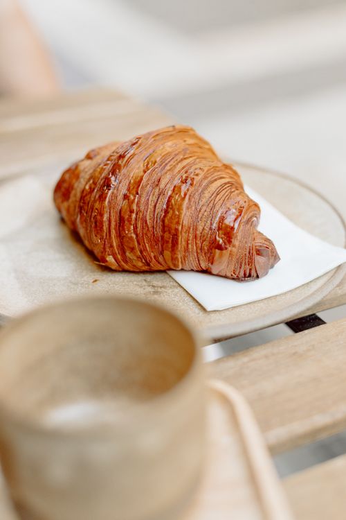 Free A delicious croissant on a rustic wooden table at a café in Budapest, perfect for breakfast. Stock Photo