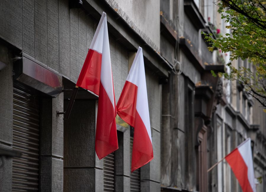 Polish flags hanging on a historic urban building, symbolizing national pride.