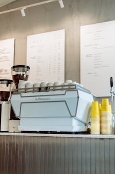 Modern café counter in Budapest featuring a La Marzocco coffee machine with cups and takeaway cups.