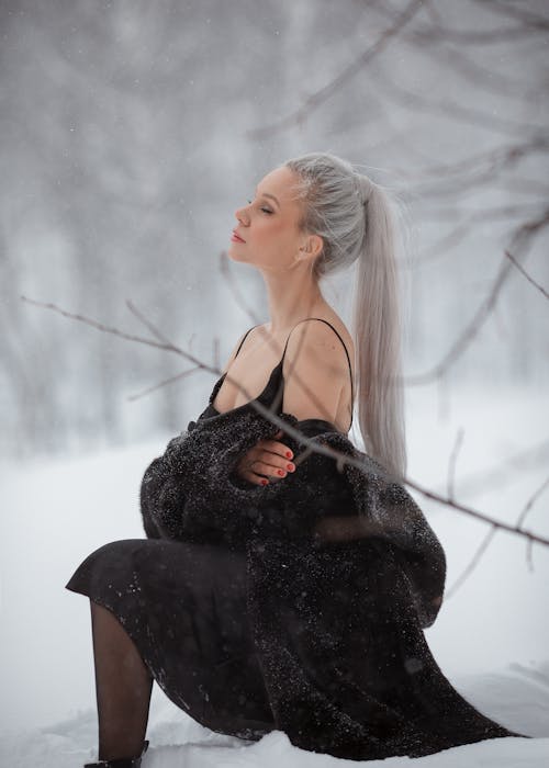 Woman in Fur Wearing a Long Ponytail Sitting in the Snow