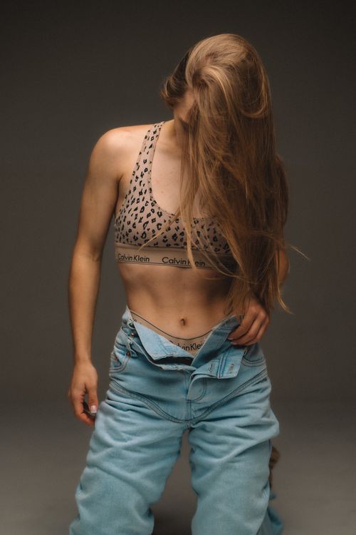 Free Model posing in trendy lingerie and jeans in a studio setting, showcasing casual fashion. Stock Photo