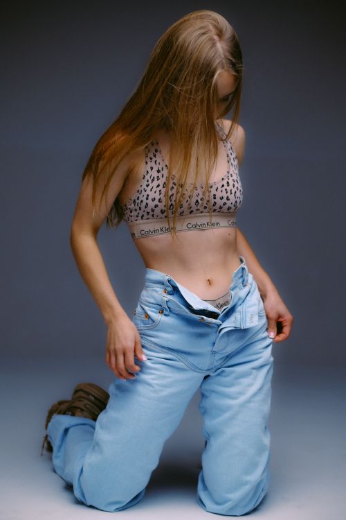 Free Woman modeling in bralette and jeans during studio photoshoot. Stock Photo