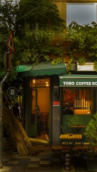 A cozy small café with green sunshade and lush plants on a city street.