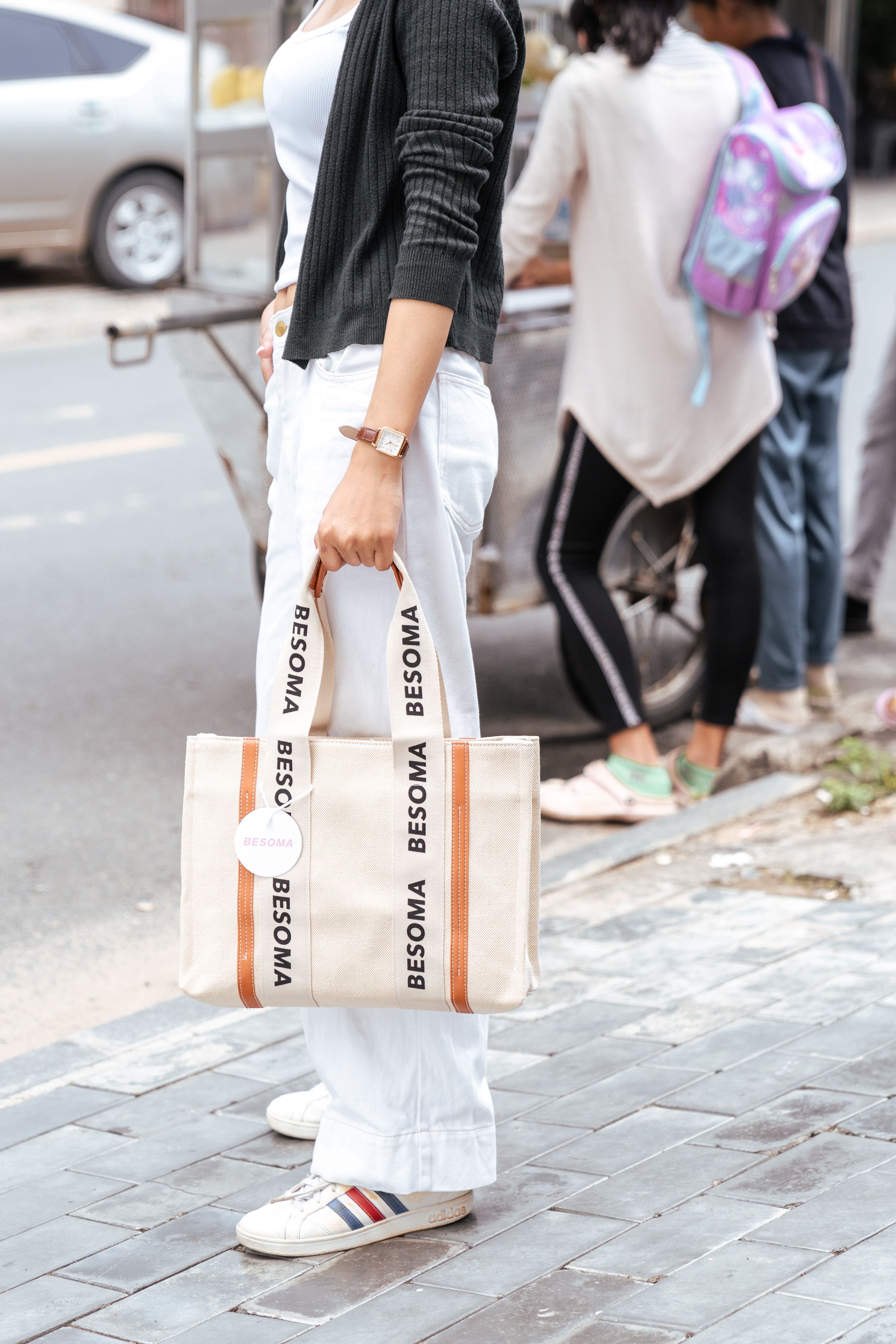 Mulher estilosa com bolsa de lona na calçada da cidade, incorporando a vibe da moda urbana.