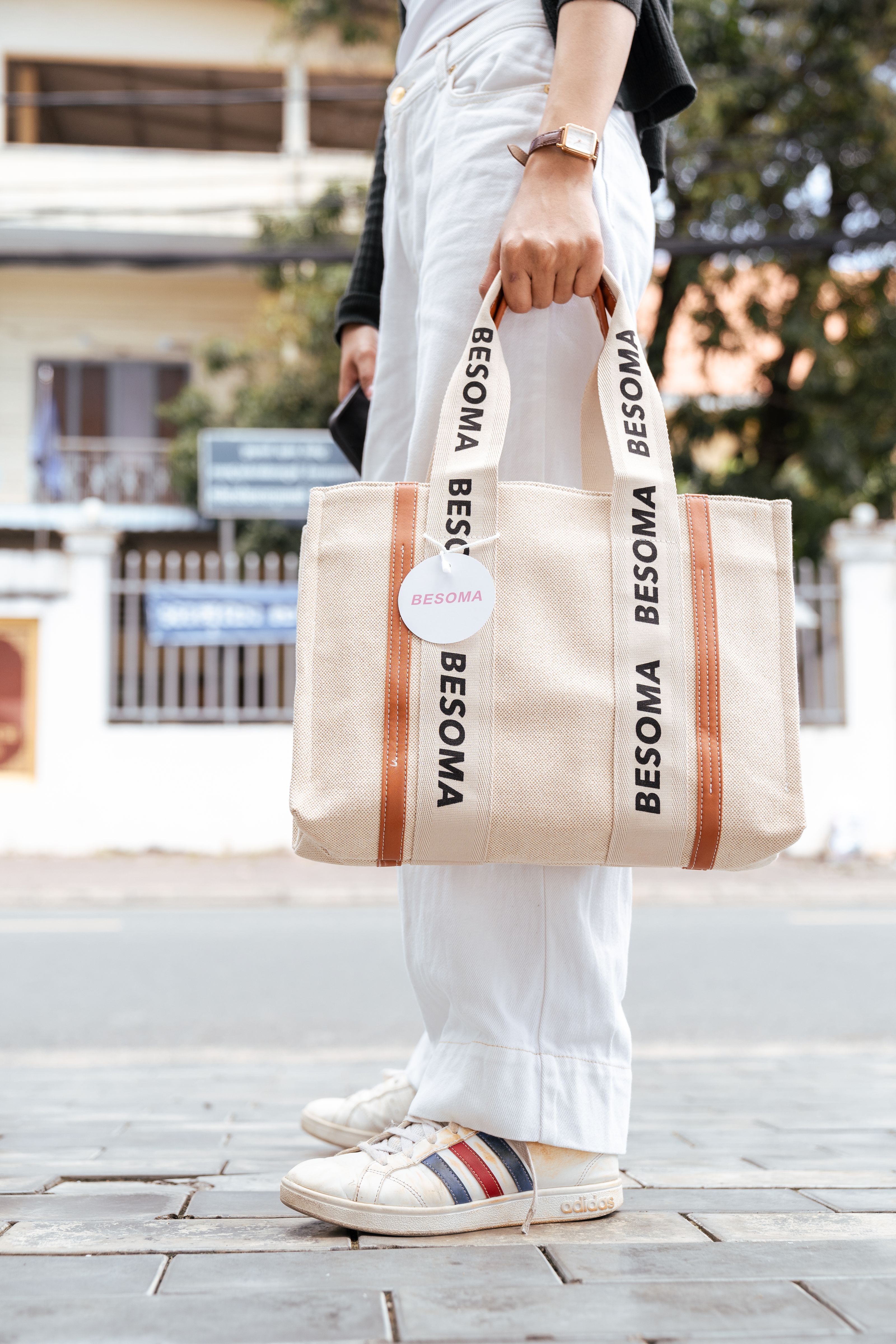 Mulher fashionista em traje casual segurando uma bolsa de lona estilosa na calçada da cidade.