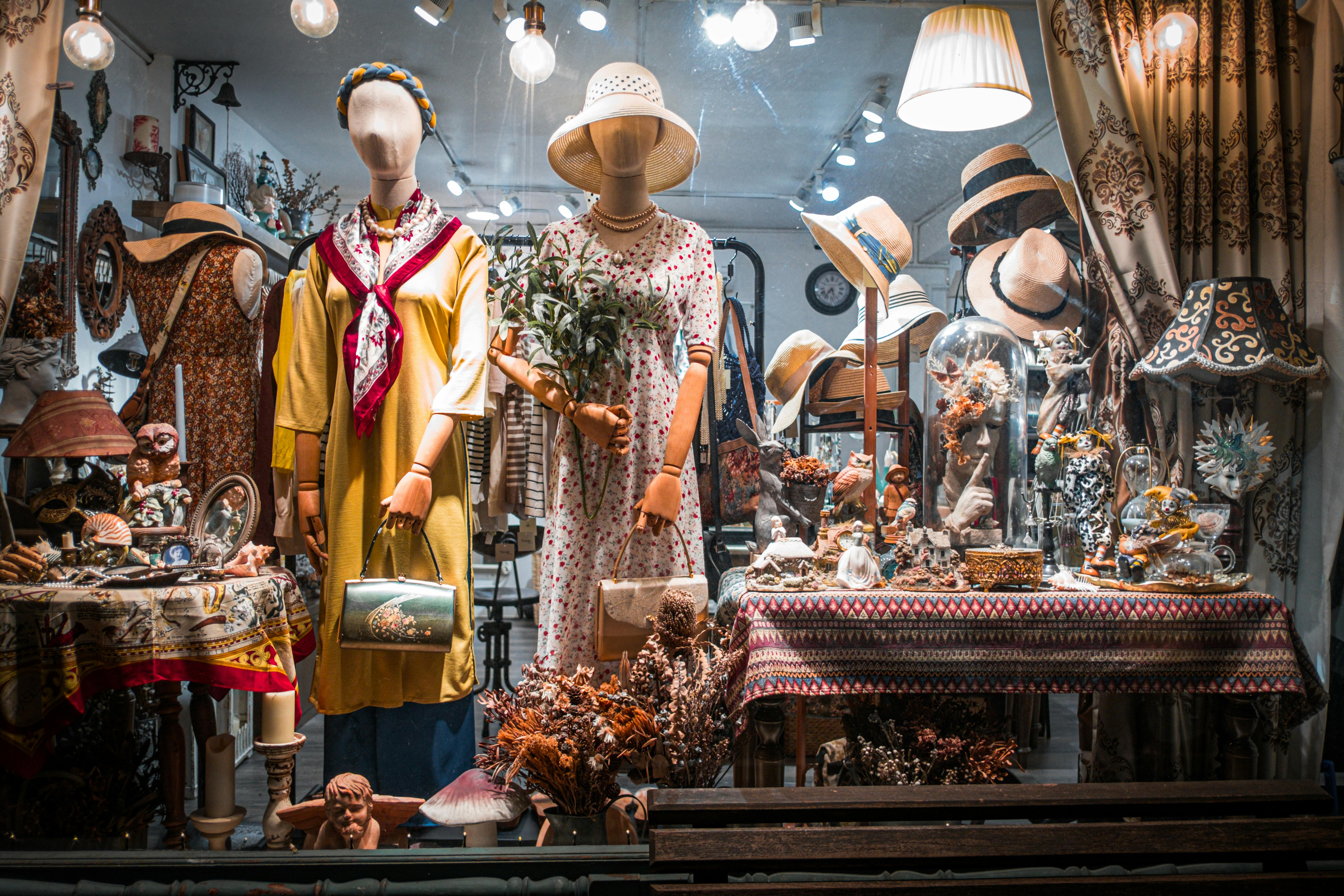 Free Charming vintage boutique window featuring dressed mannequins and ornate decor. Stock Photo
