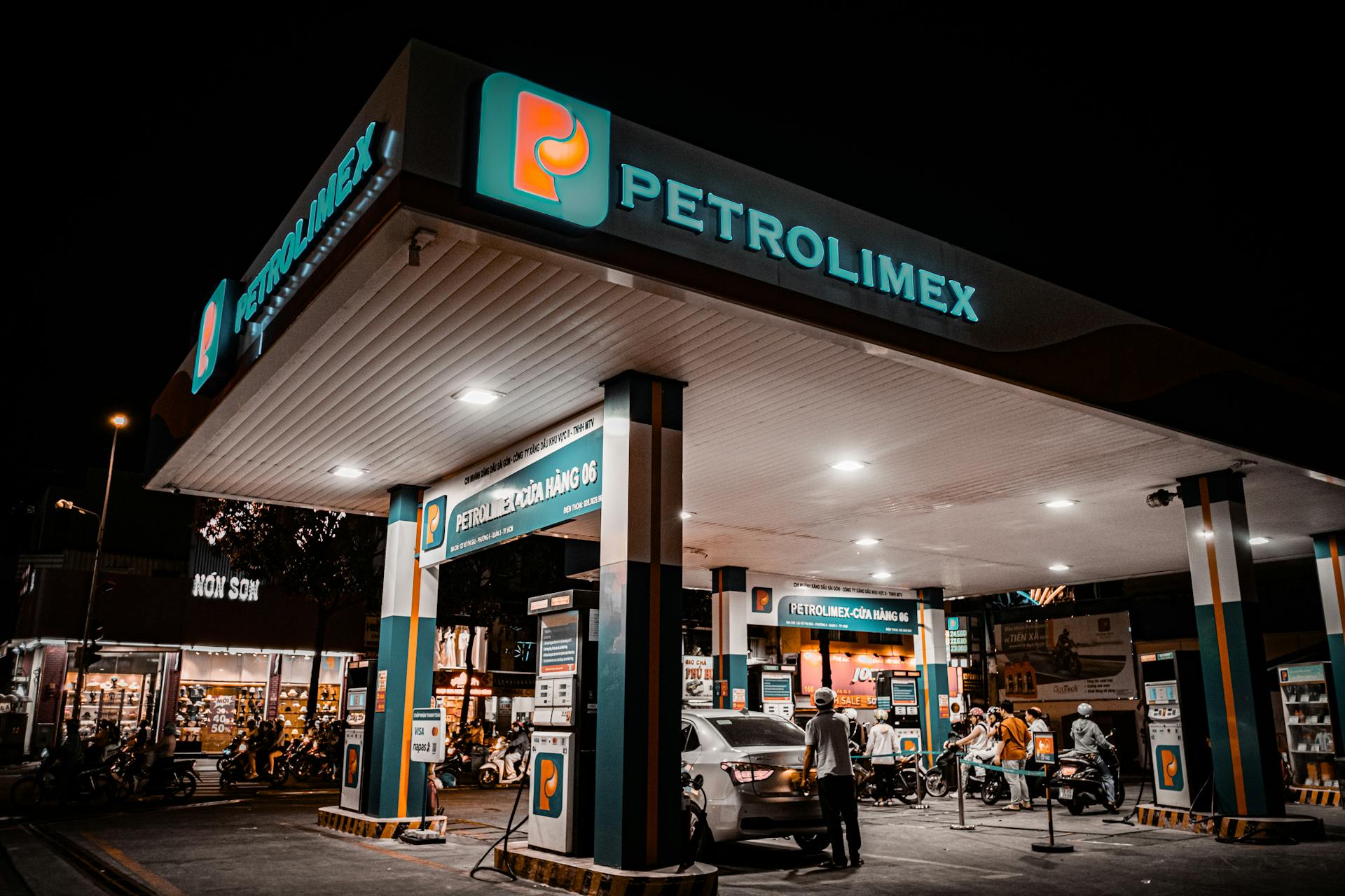 Night view of a Petrolimex gas station with customers fueling up.