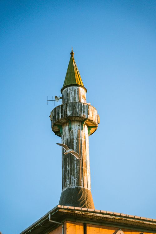 Free Wooden minaret of Makbul Ibrahim Pasha Mosque in Istanbul with a bird flying by at sunset. Stock Photo