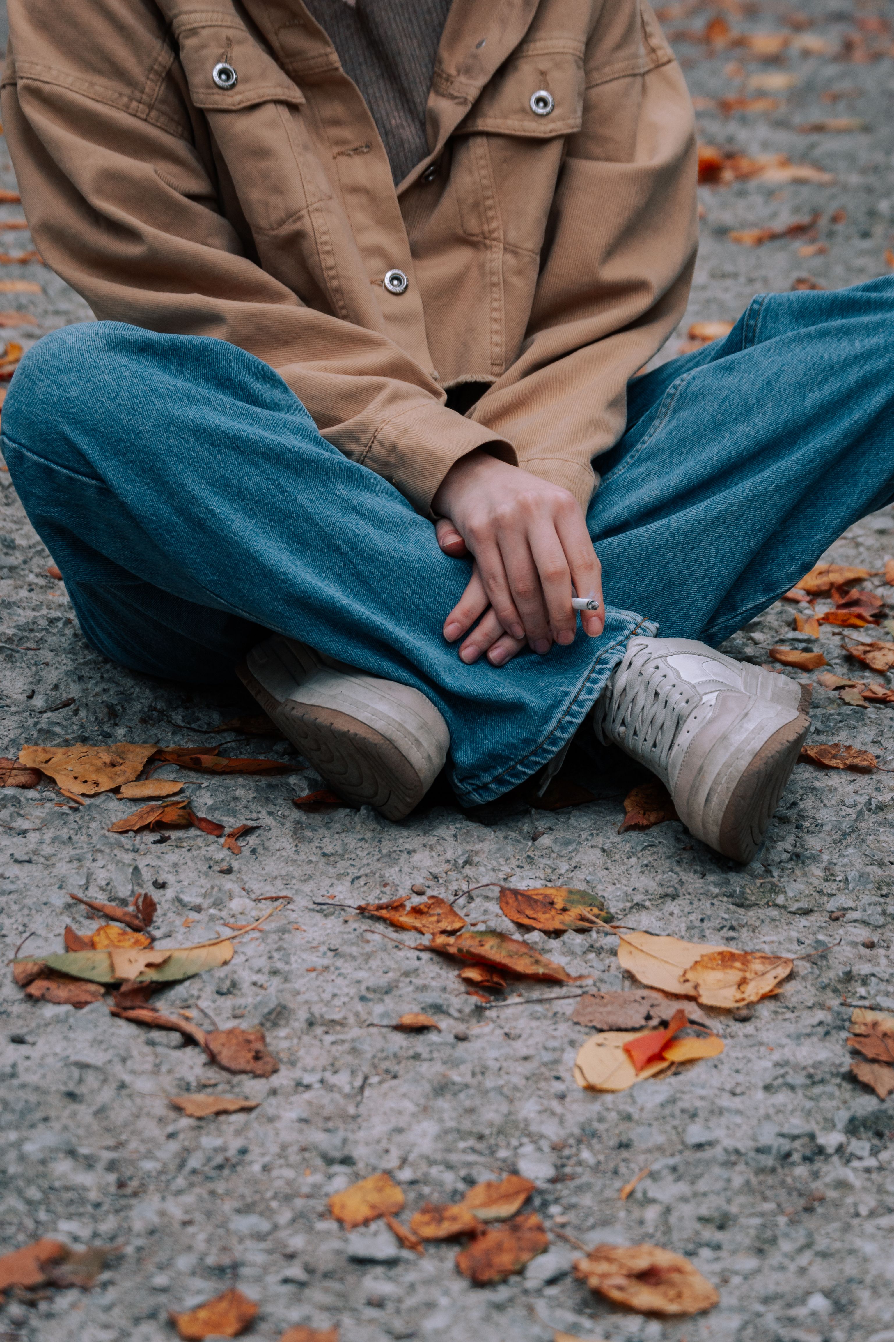 Woman in Jacket and Jeans Sitting on Pavement · Free Stock Photo