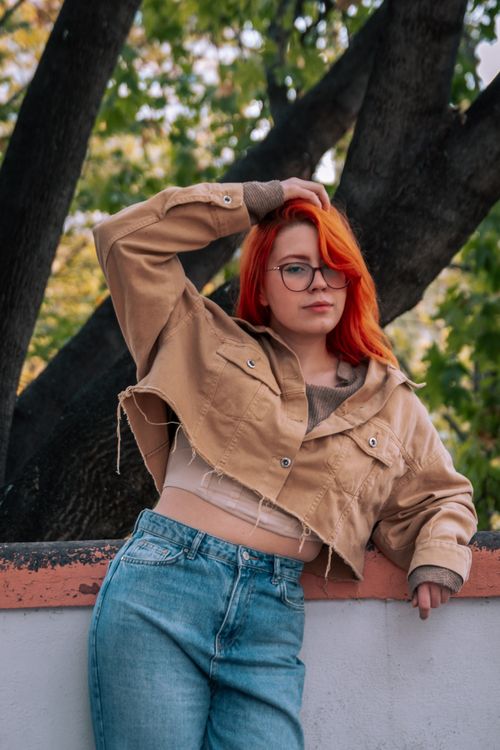 Free Portrait of a stylish redhead woman in a casual autumn setting, wearing a jacket and jeans. Stock Photo