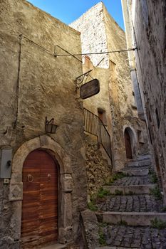 Charming narrow alley with stone steps and ancient architecture in Castel del Monte, Italy.