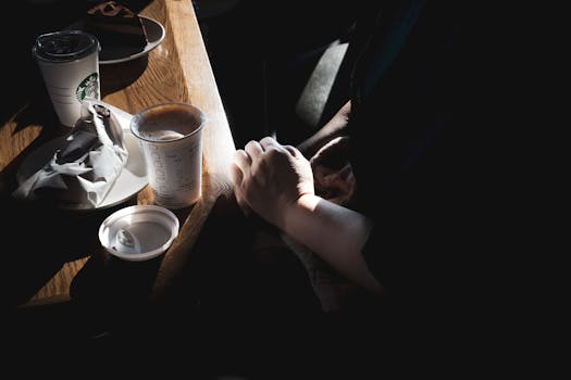 Hands resting on table with coffee cups in a cozy café setting, capturing warmth and relaxation.