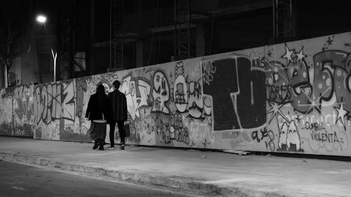 People Walking Next to Graffiti in Black and White