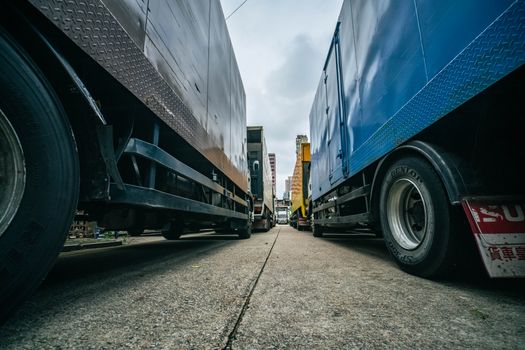 Captivating low-angle perspective of multiple trucks lined up on a street in Hong Kong.
