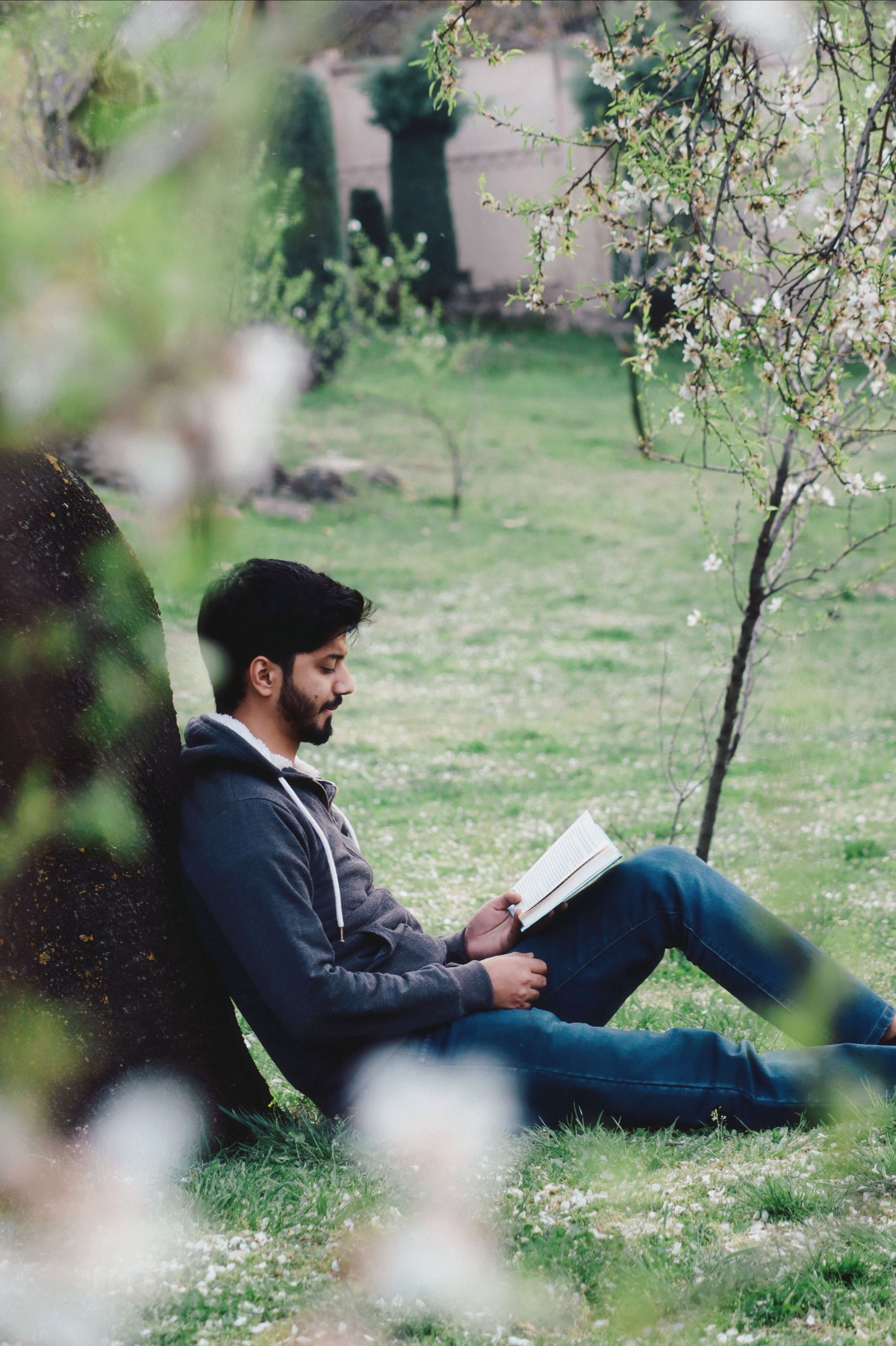 Young Man Sitting on a Grass and Reading a Book · Free Stock Photo