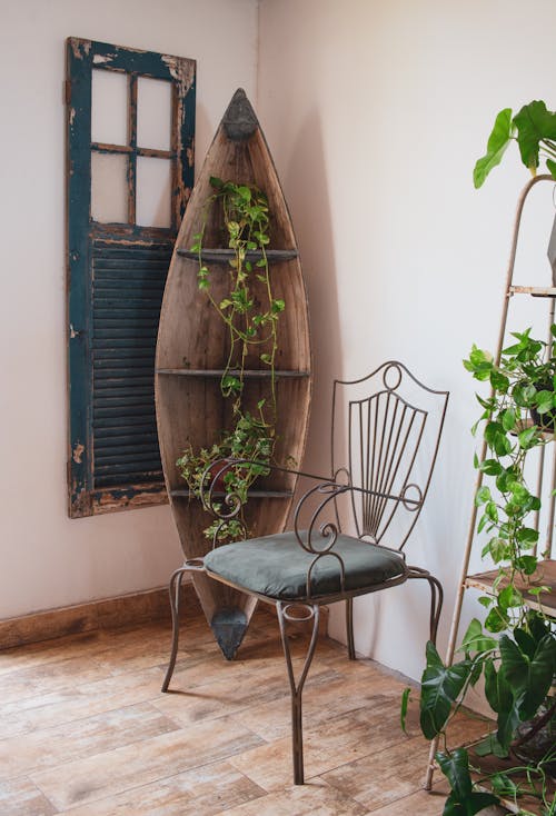 Wooden Boat Converted into a Shelves for Potted Ivies Next to Decoration from an Old Door