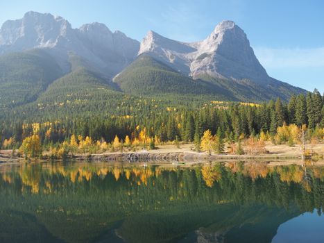 Stunning autumn reflections of mountains and trees on Alberta lake.