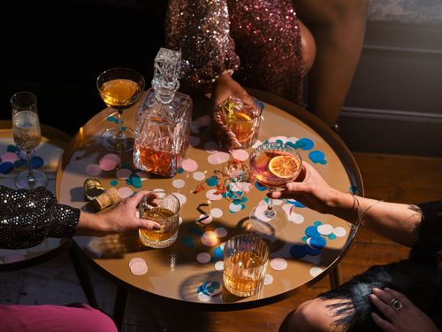 Free Stylish party setup with drinks, confetti, and a crystal carafe on a round table. Stock Photo