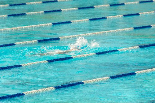 Free Swimmer in action making a splash in clear blue swimming pool lanes. Stock Photo
