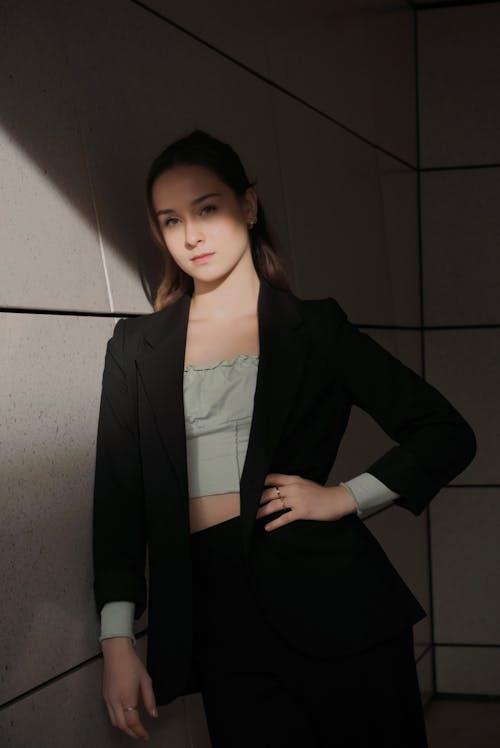 Woman in a Suit Jacket Leaning on a Wall with a Hand on a Hip