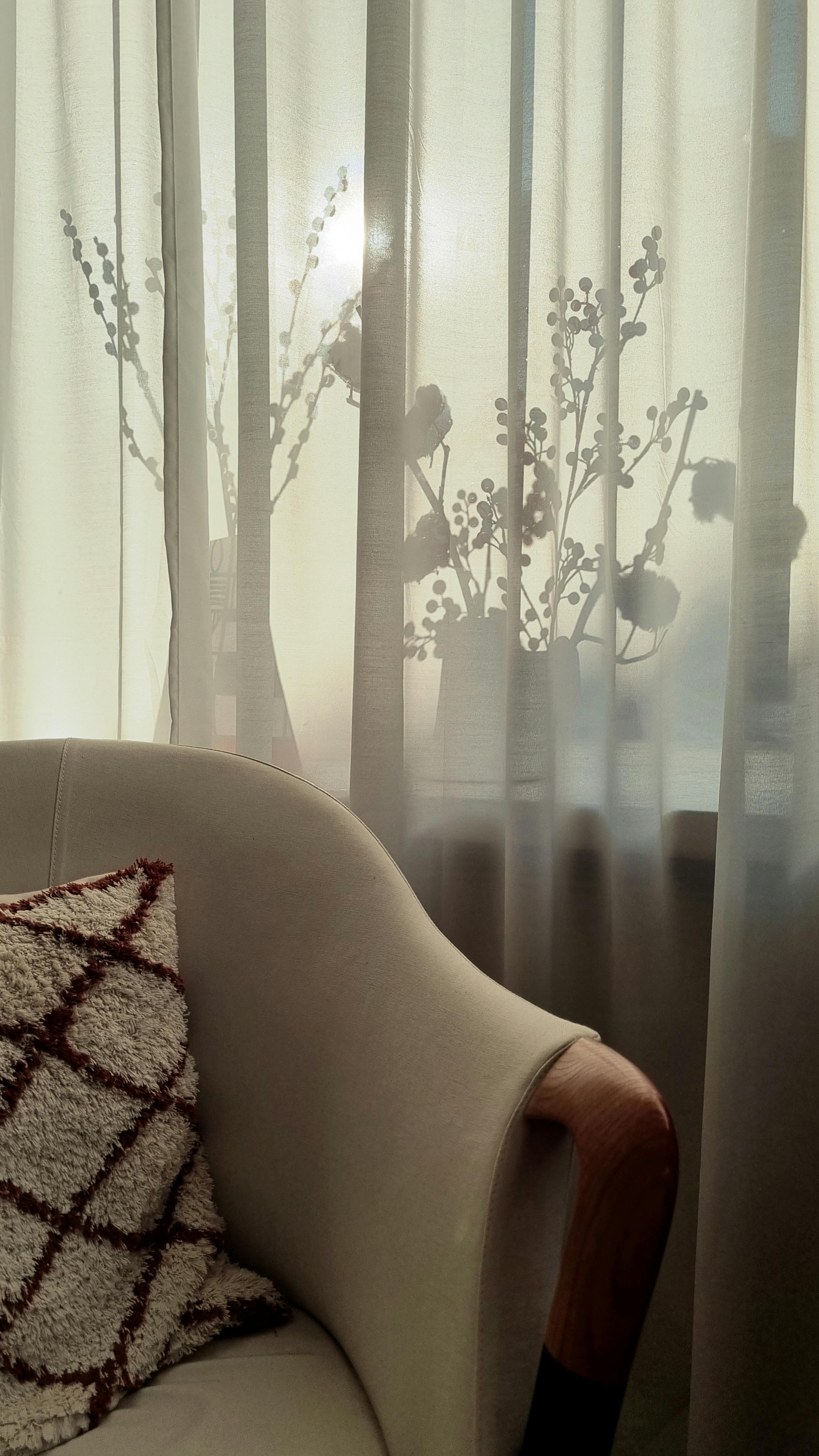 Warm interior view with floral silhouettes behind sheer curtains, exuding tranquility.