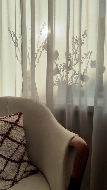 Warm interior view with floral silhouettes behind sheer curtains, exuding tranquility.