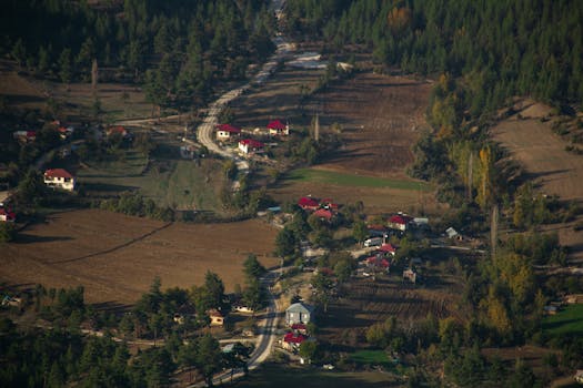 Aerial view of a picturesque village in Aladağ, Adana, Türkiye with winding roads and lush forests.
