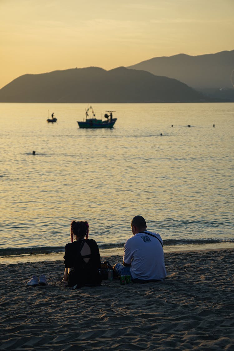 A Couple Sitting On The Beach